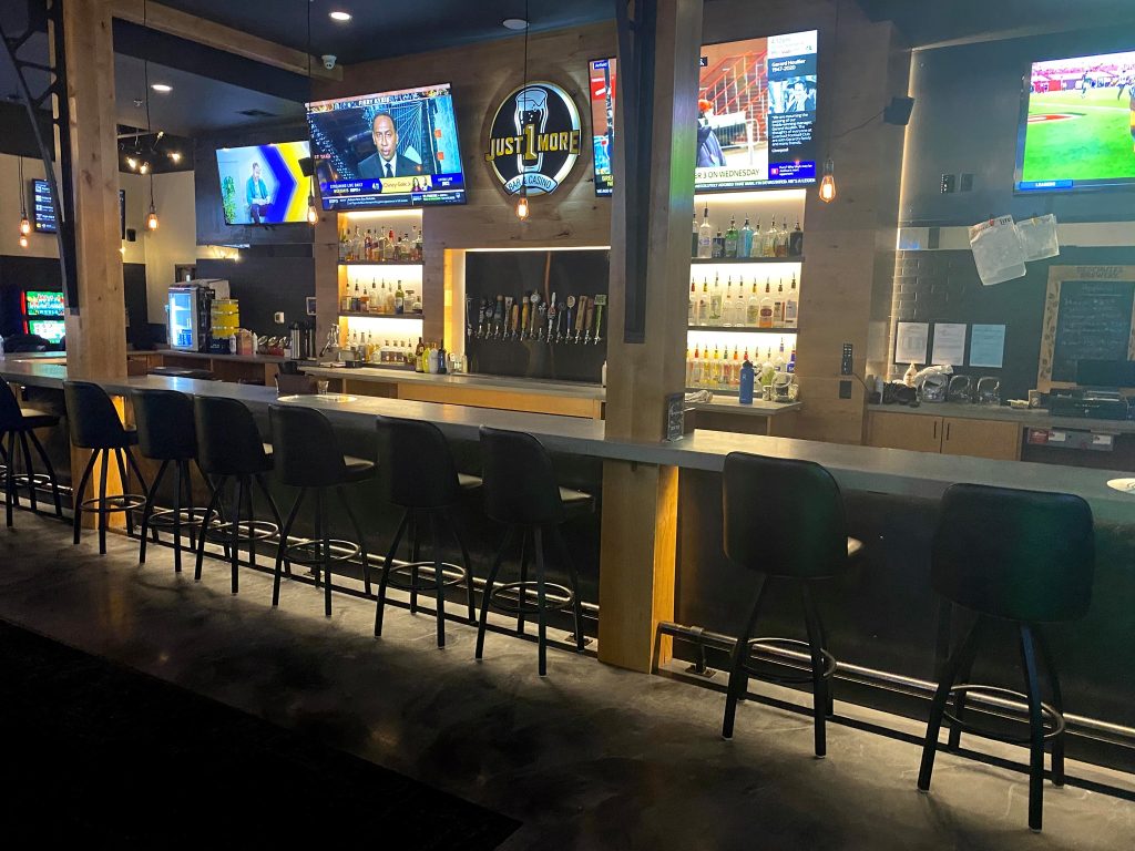 Bar stools and flat screen TVs inside Just 1 More Bar and Casino