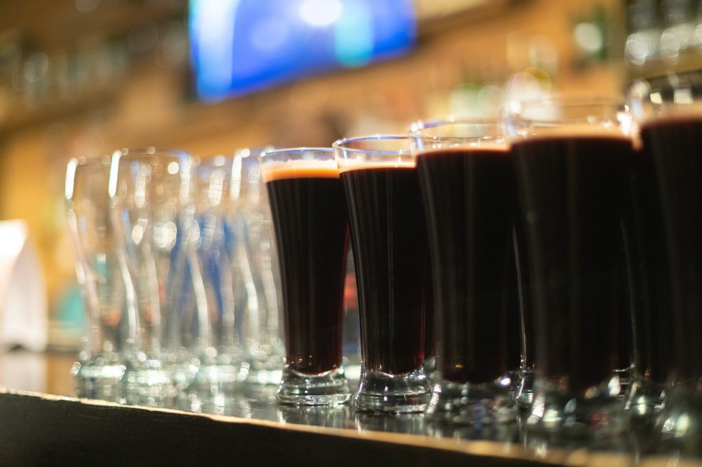 Glasses of dark beer lined up on a bar counter